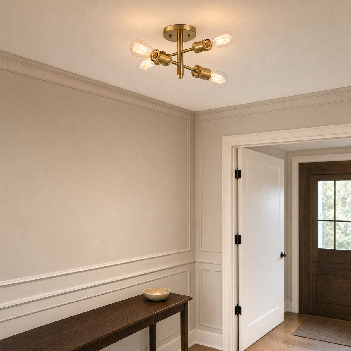 Antique brass four-light ceiling fixture illuminated in a paneled entry hallway