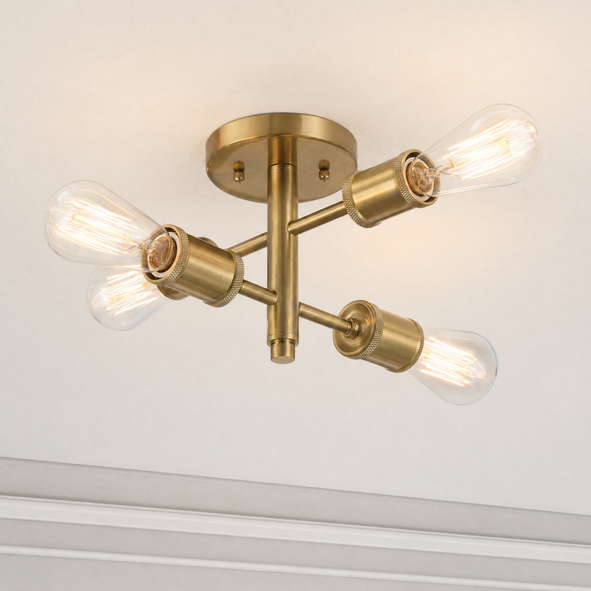 Antique brass four-light semi-flush ceiling light with illuminated clear bulbs, close-up