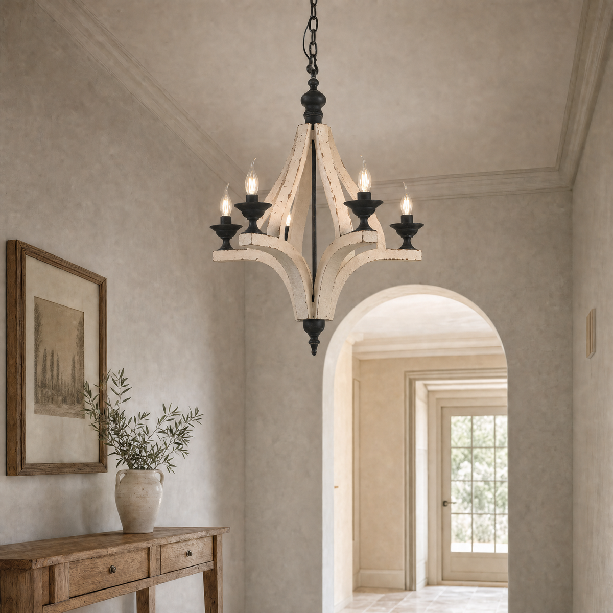 Distressed cream farmhouse chandelier with warm candle bulbs in an arched entry hall