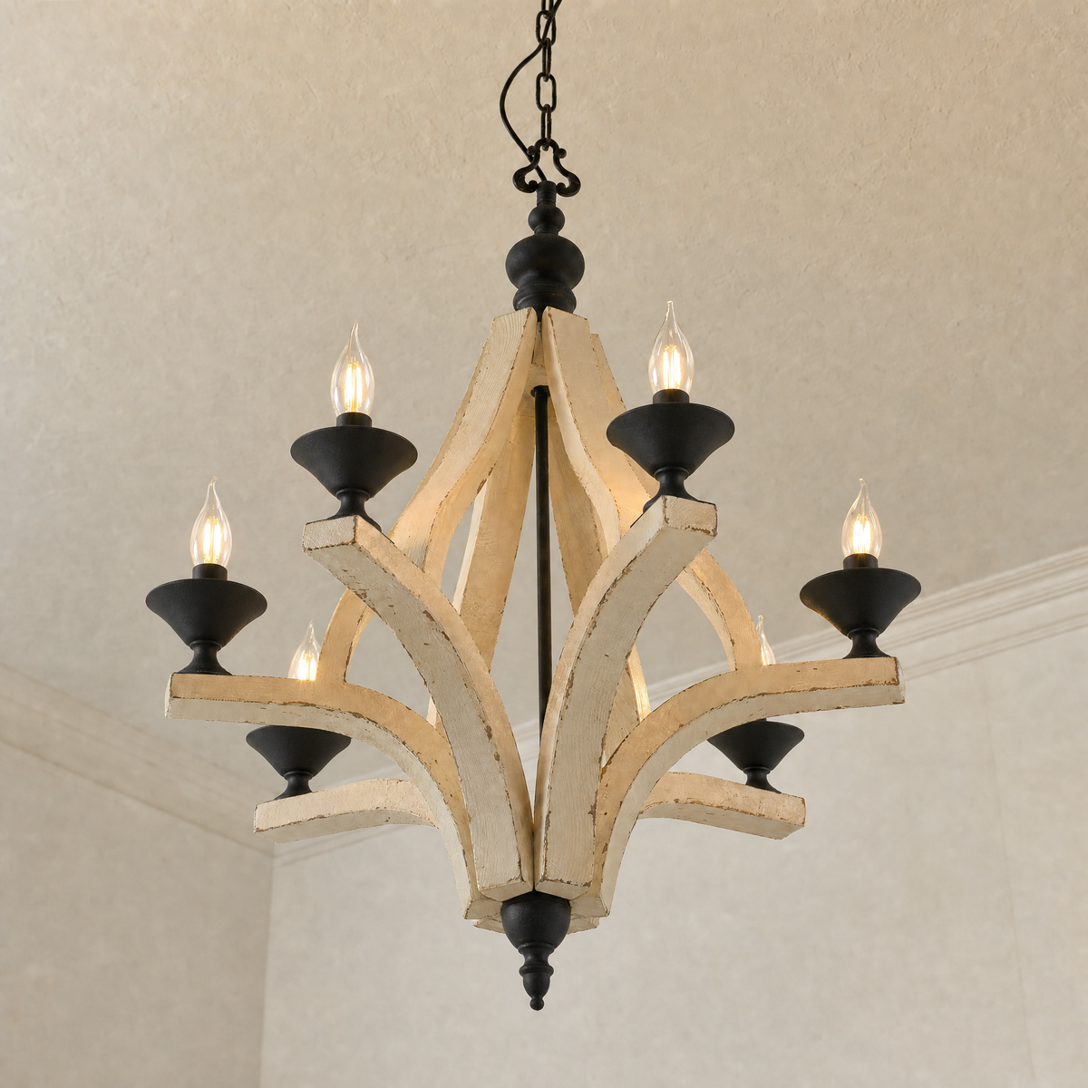 Low-angle view of the six wooden arms and black iron candle cups of the farmhouse chandelier