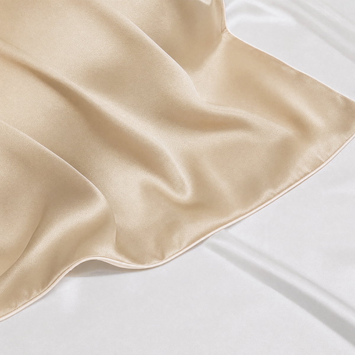 Close-up of Champagne mulberry silk pillowcase corner and piped seam on white bedding