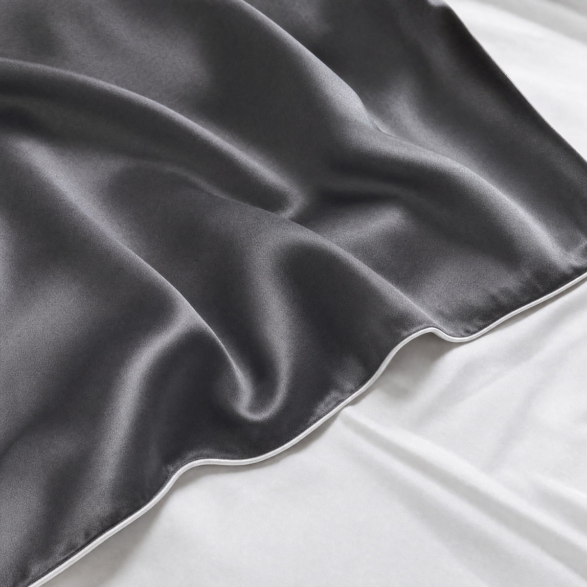 Close-up of Dark Gray mulberry silk pillowcase corner and piped seam on white bedding