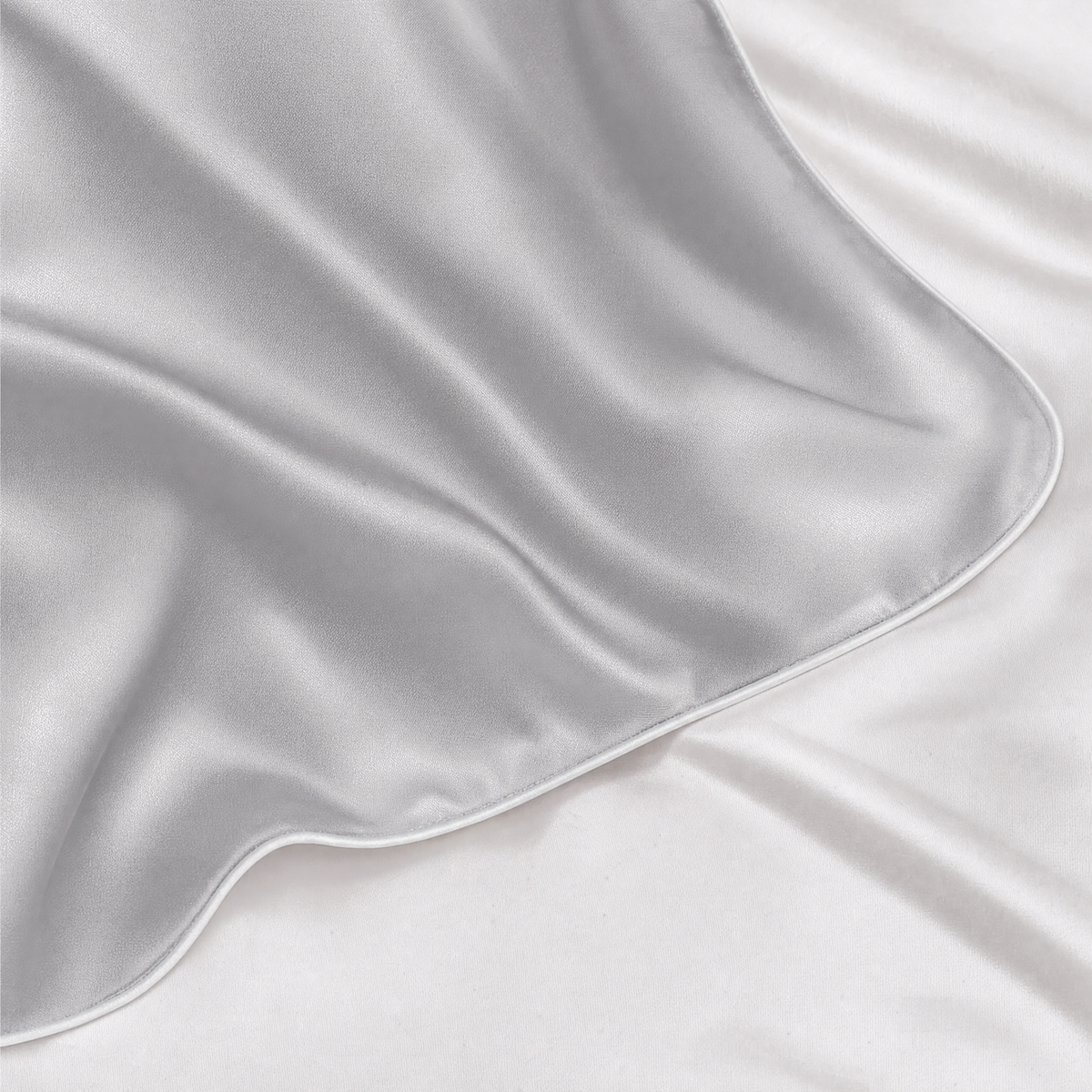 Close-up of Silver Gray mulberry silk pillowcase corner and piped seam on white bedding