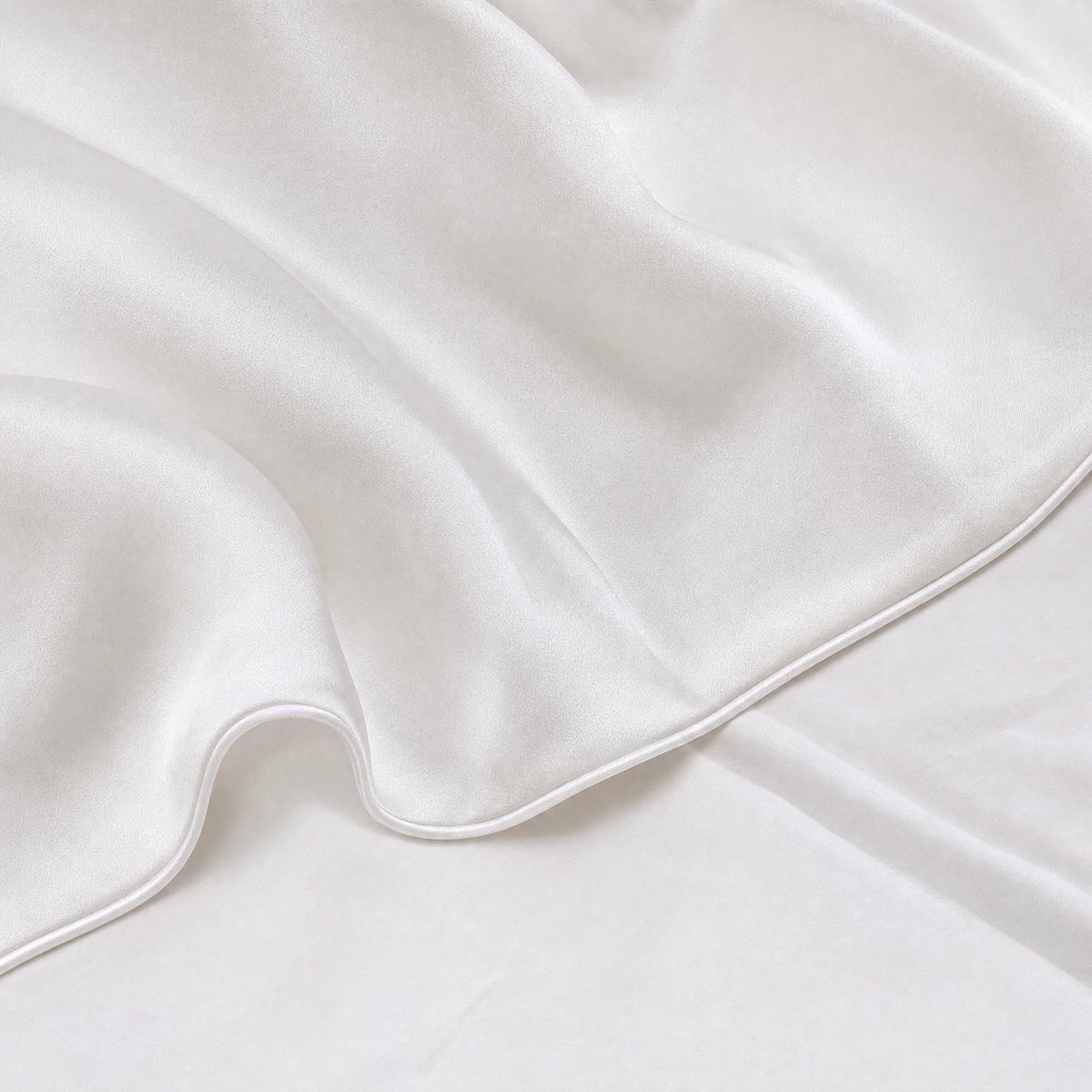 Close-up of White mulberry silk pillowcase corner and piped seam on white bedding